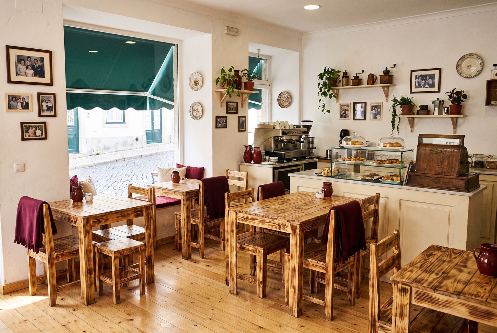 Cosy interior of Portuguese Flavours with rustic wooden tables and a green awning through the window